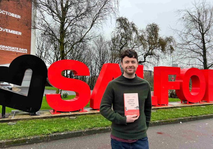 Pic shows Josh with book standing in front of the Salford sign