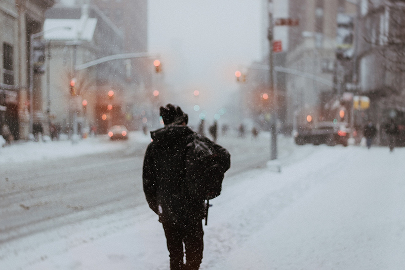 Lone person walking in the snow in the city. No-one else in the picture.
