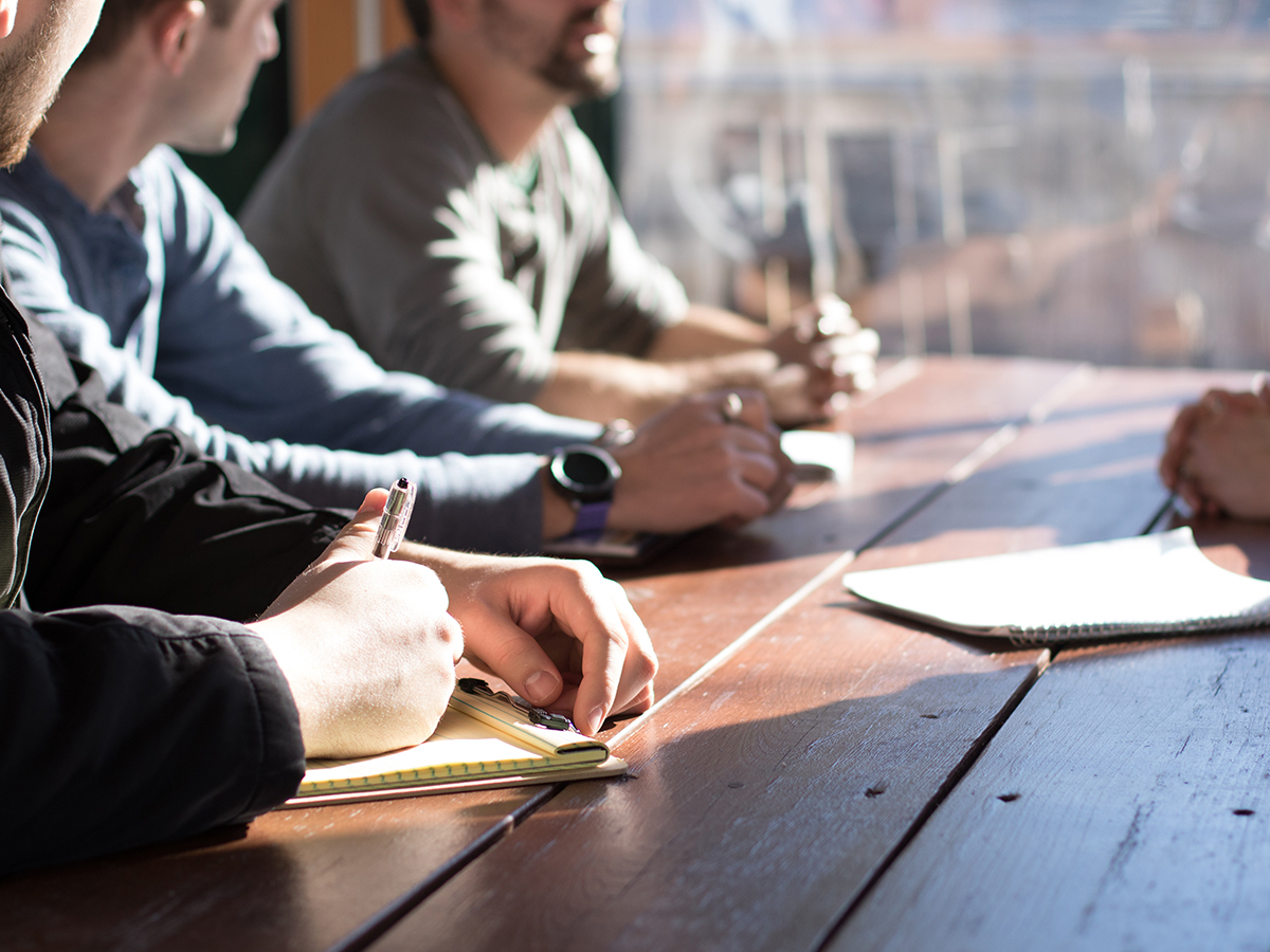 A table of students taking notes whilst discussing a project