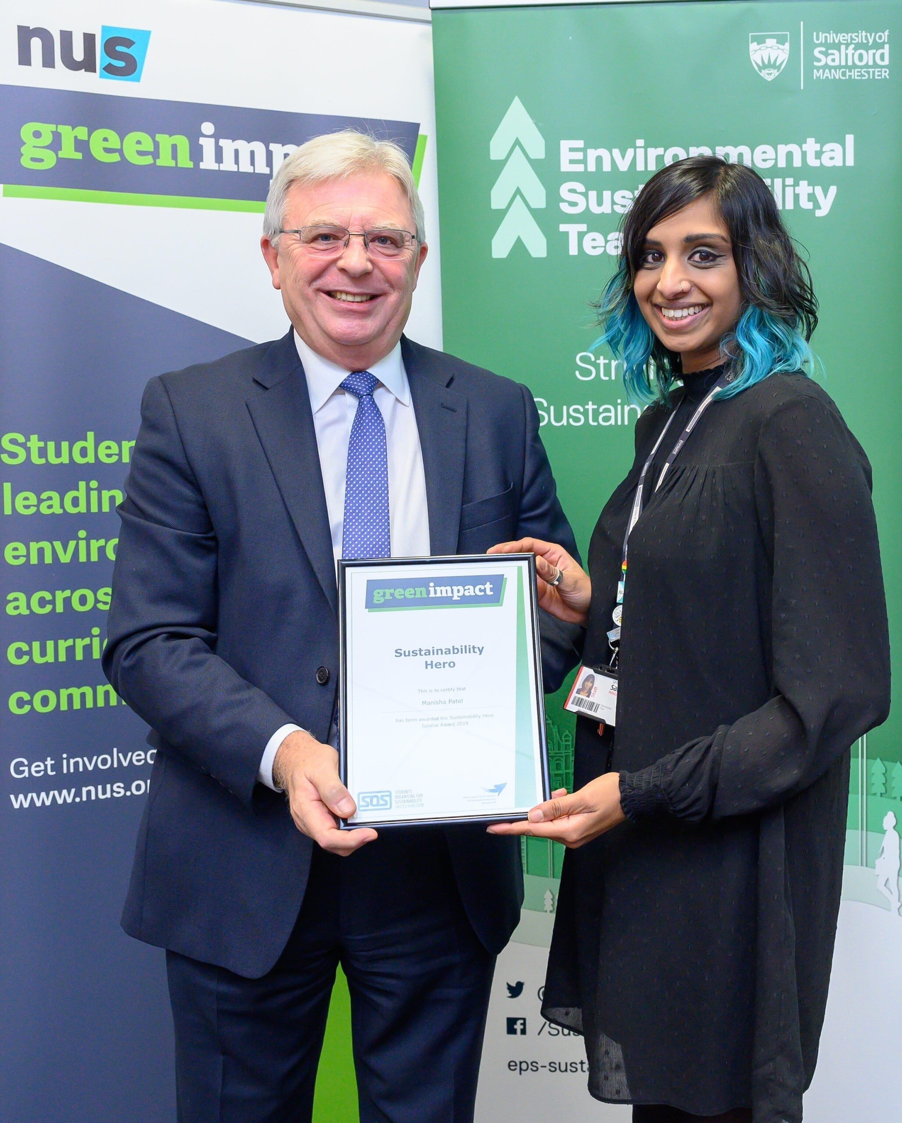 Two people stood in front of banner with award