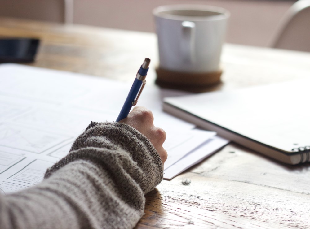 A person writes at a desk