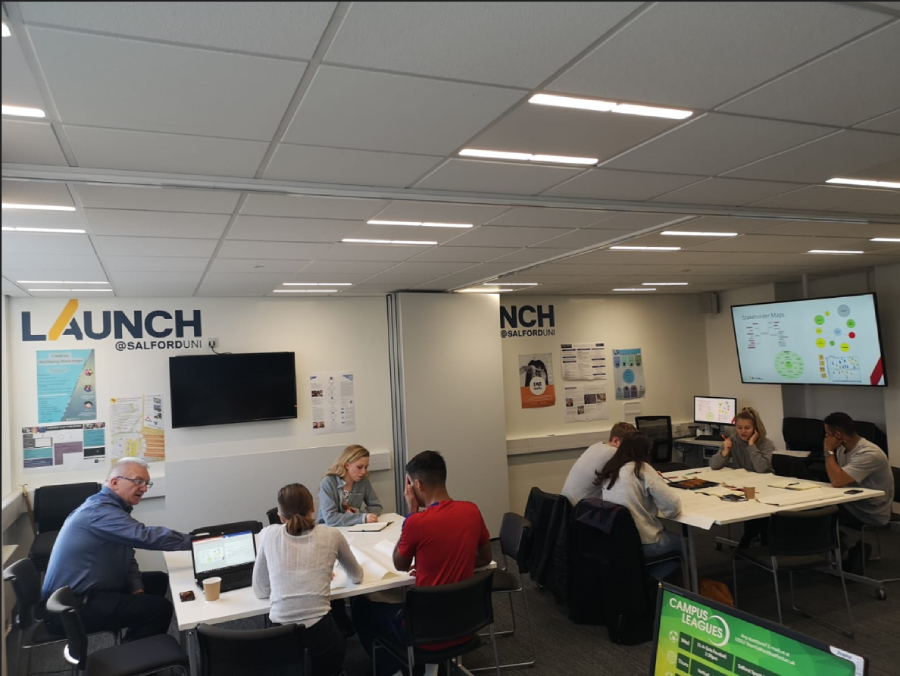 8 seated staff members working in the Launch@Salford office, University of Salford