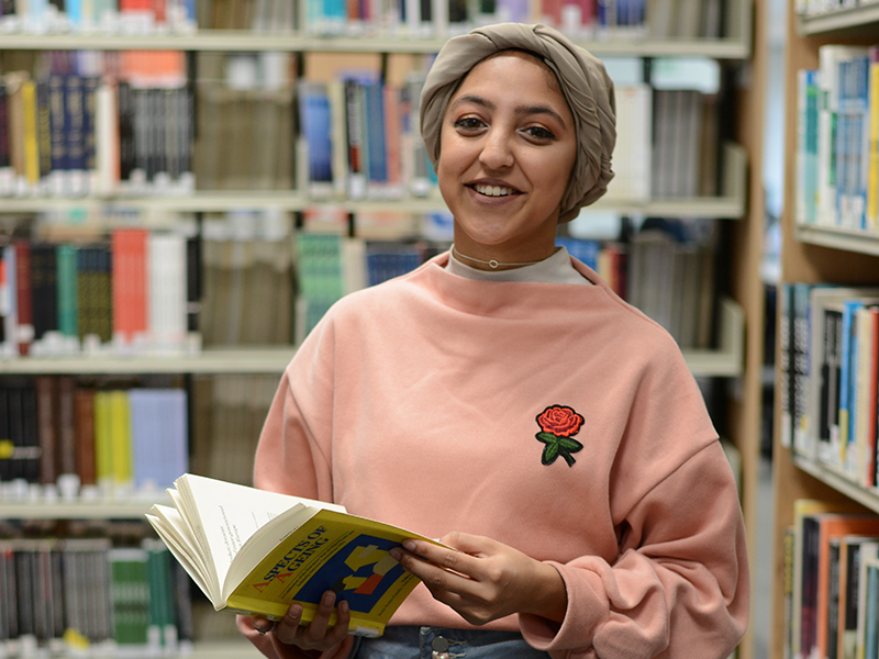 Student with an open book in the Clifford Whitworth Library at the University of Salford