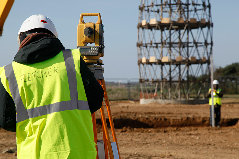 Surveying degree student using construction equipment in a field