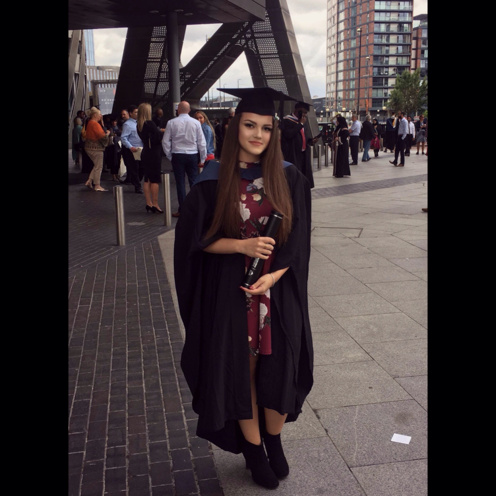 A photograph of Maria Efimova in a graduation gown outside the Lowry Theatre