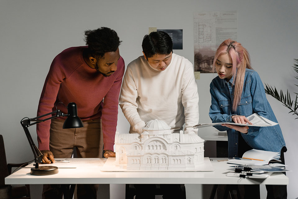 Image of 3 people looking at a 3D model of a building