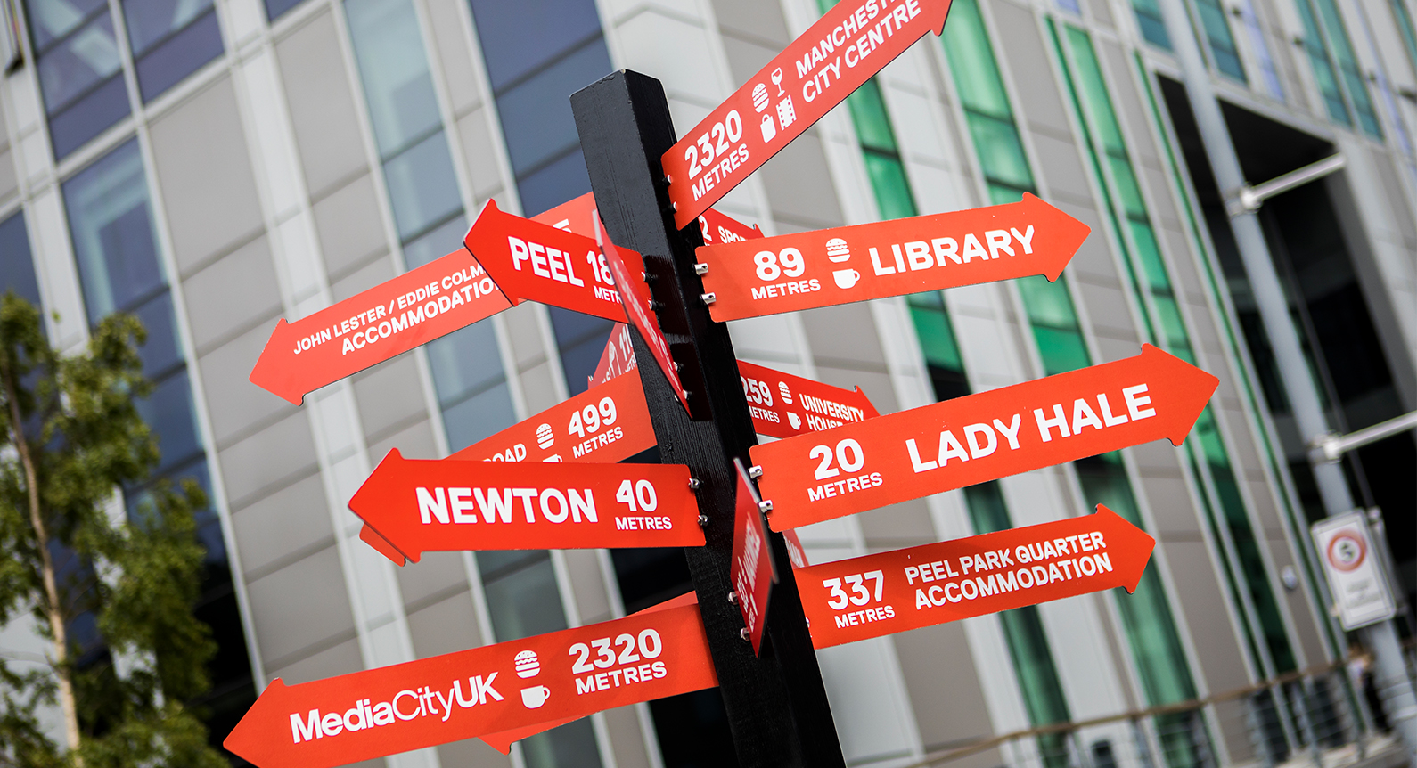 A red signpost showing destinations on Peel Park Campus, University of Salford