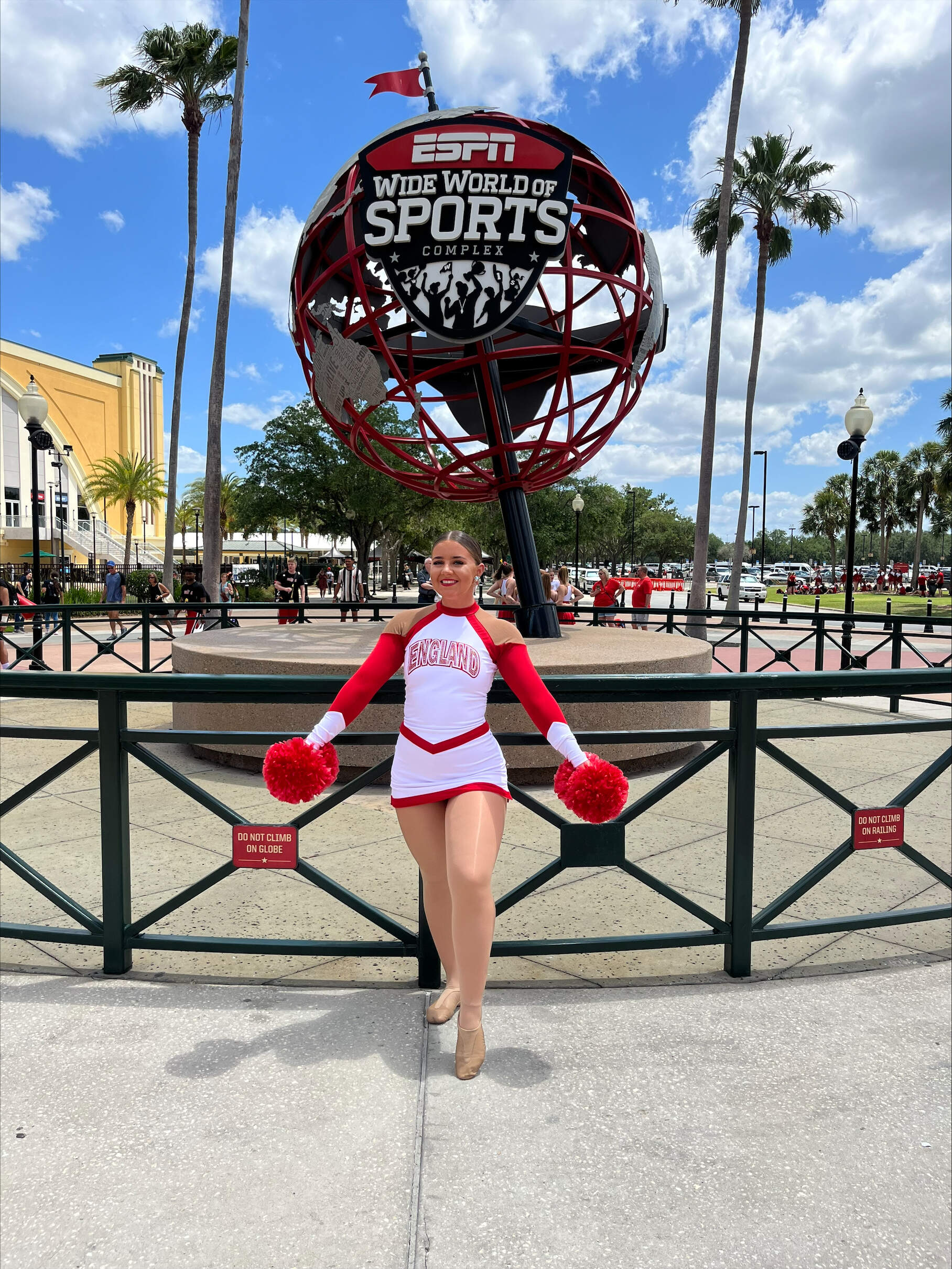 A cheerleader posing in front of the ESPN Wide World of Sports Complex globe.
