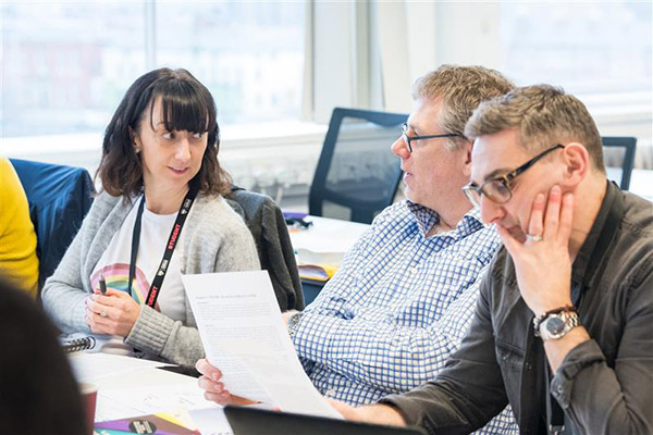 Three people sat around a table discussing notes