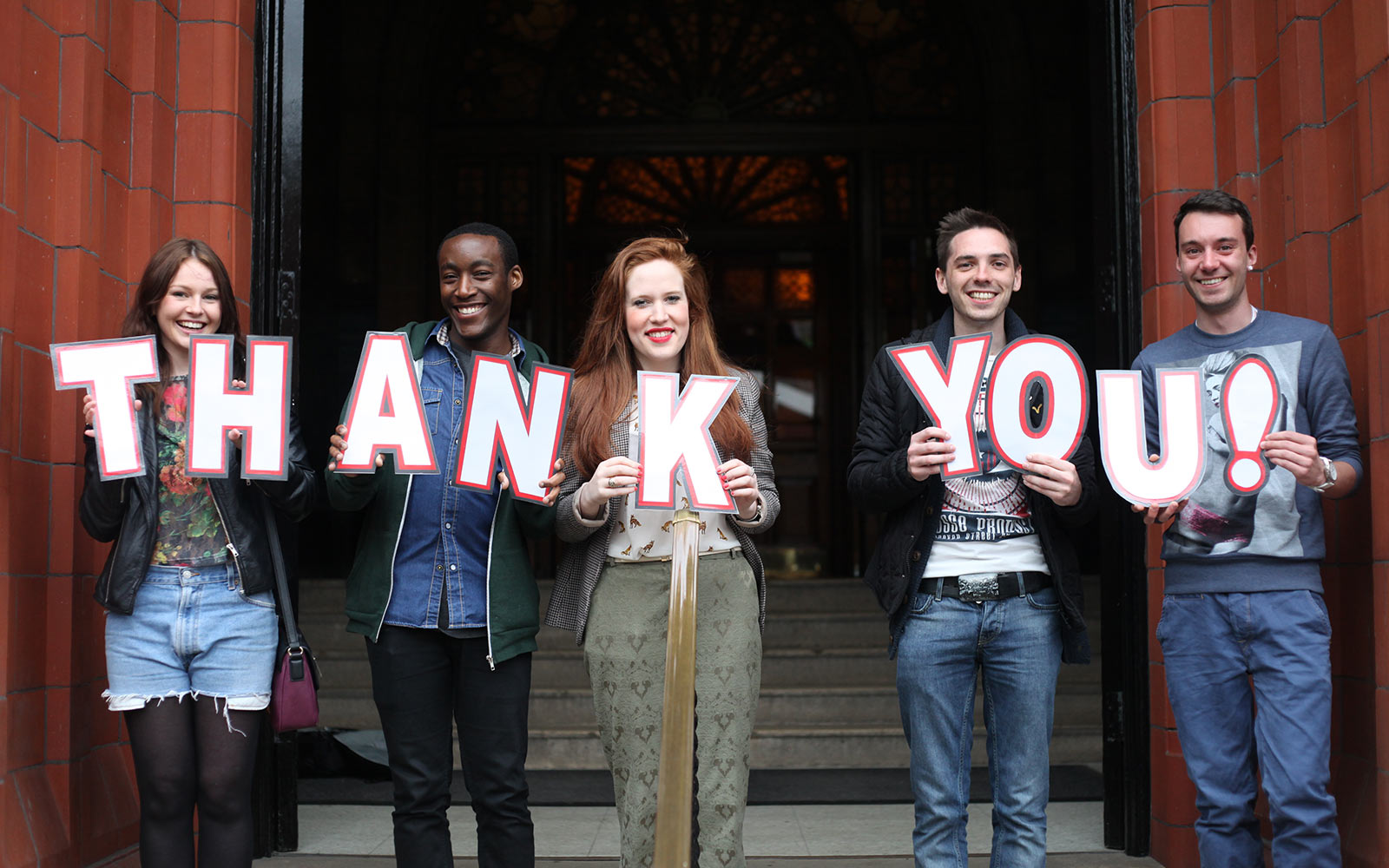 People holding letters that spell the words thank you