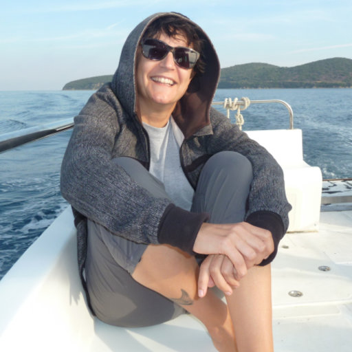 Dr Chrysoula Gubili smiling sitting on a boat in the middle of the ocean