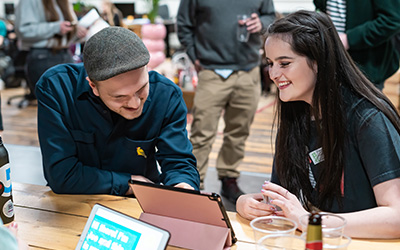 Man and woman sat at a table looking at an iPad together 