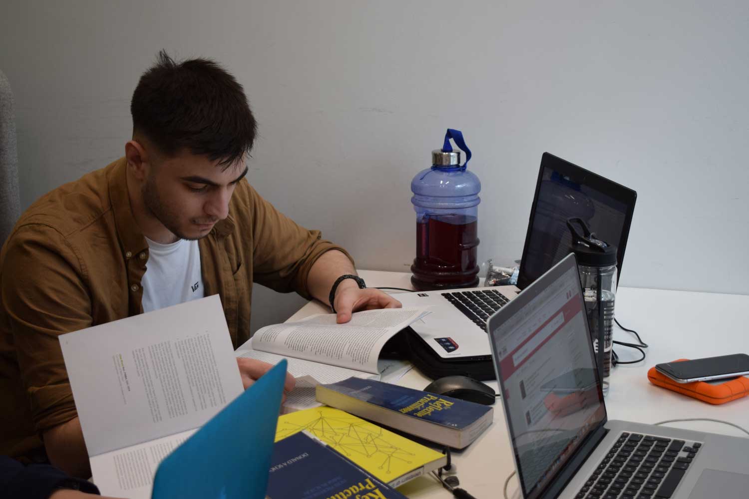 Student studying with a laptop and several books