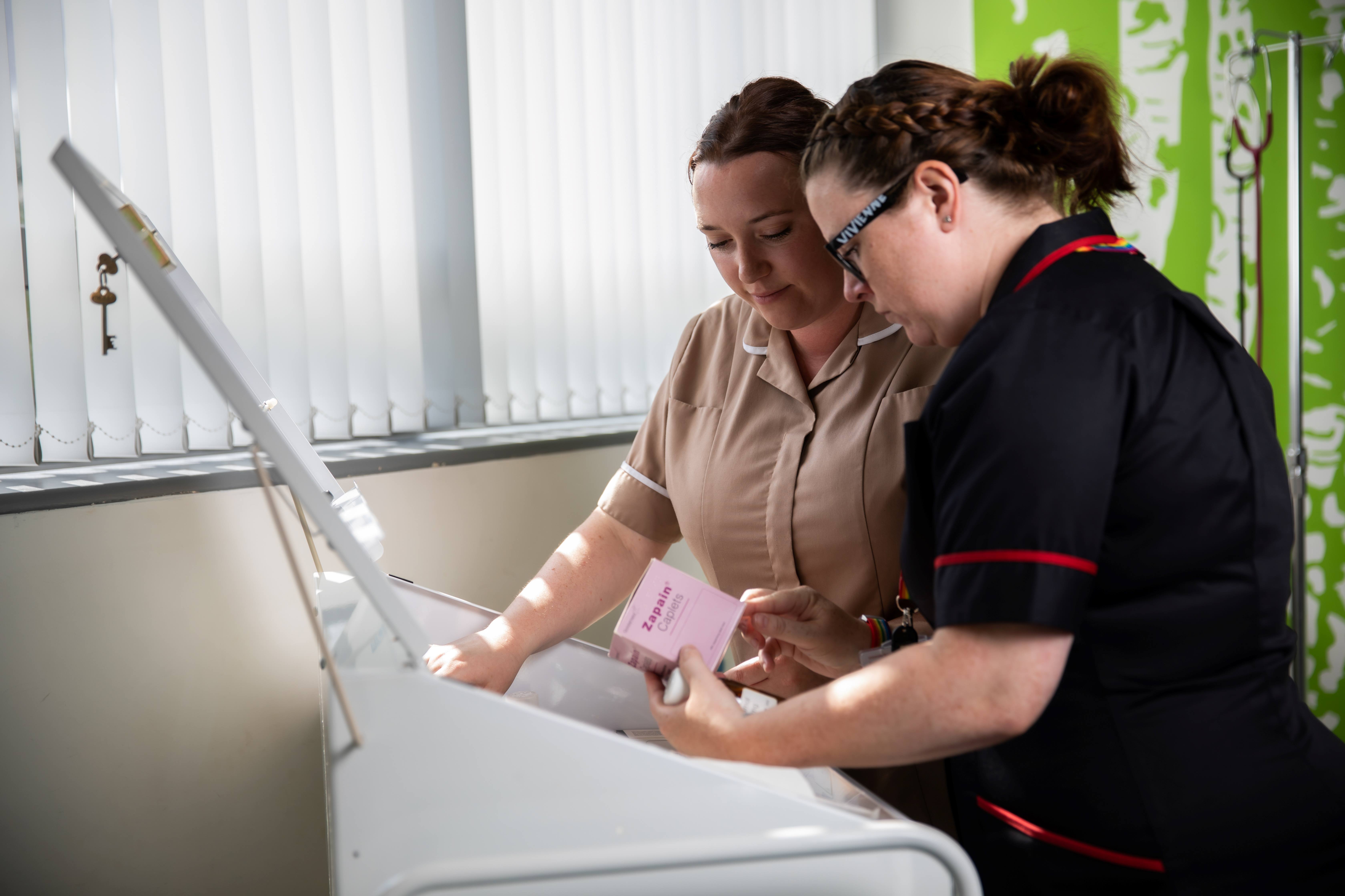 Nursing apprentice and staff member choosing medications