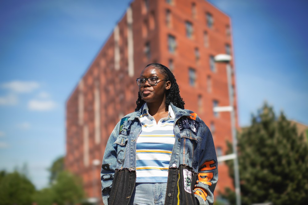 International student, Dee, outside Peel Park Quarter accommodation on a sunny day