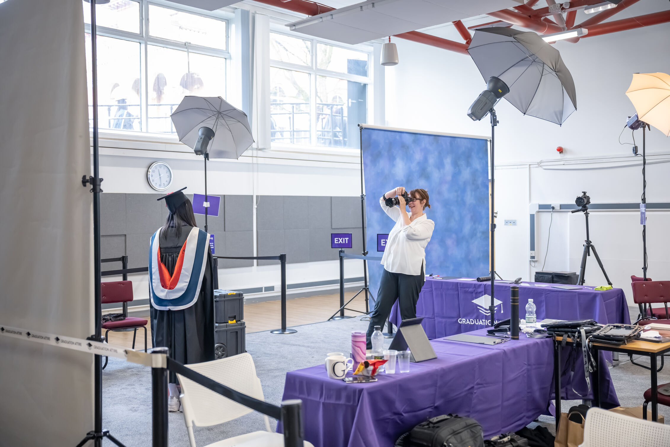 photographer takes a picture of a sole graduate in her cap and gown inside photo studio 