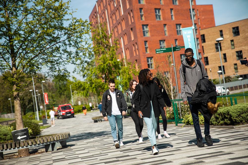 A group of students walking in front of Peel Park Quarter student accommodation