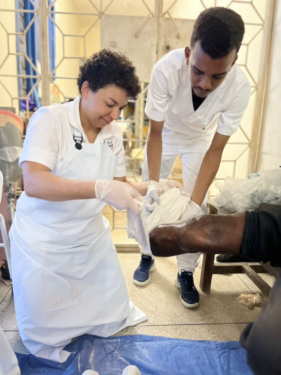 two prosthetics and orthotics students working in a practical session with a patient, both wearing a uniform. 