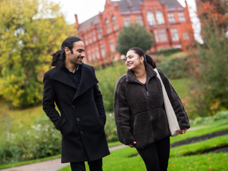 Two students walking through Peel Park Campus, University of Salford