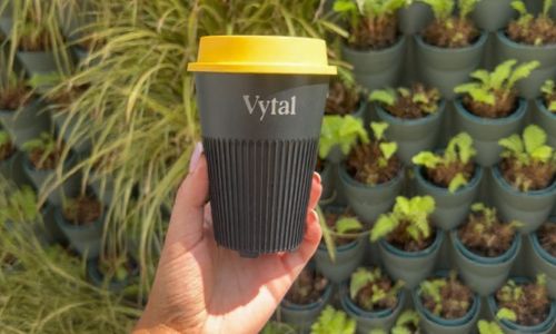 Hand holding up a Vytal branded reusable coffee cup