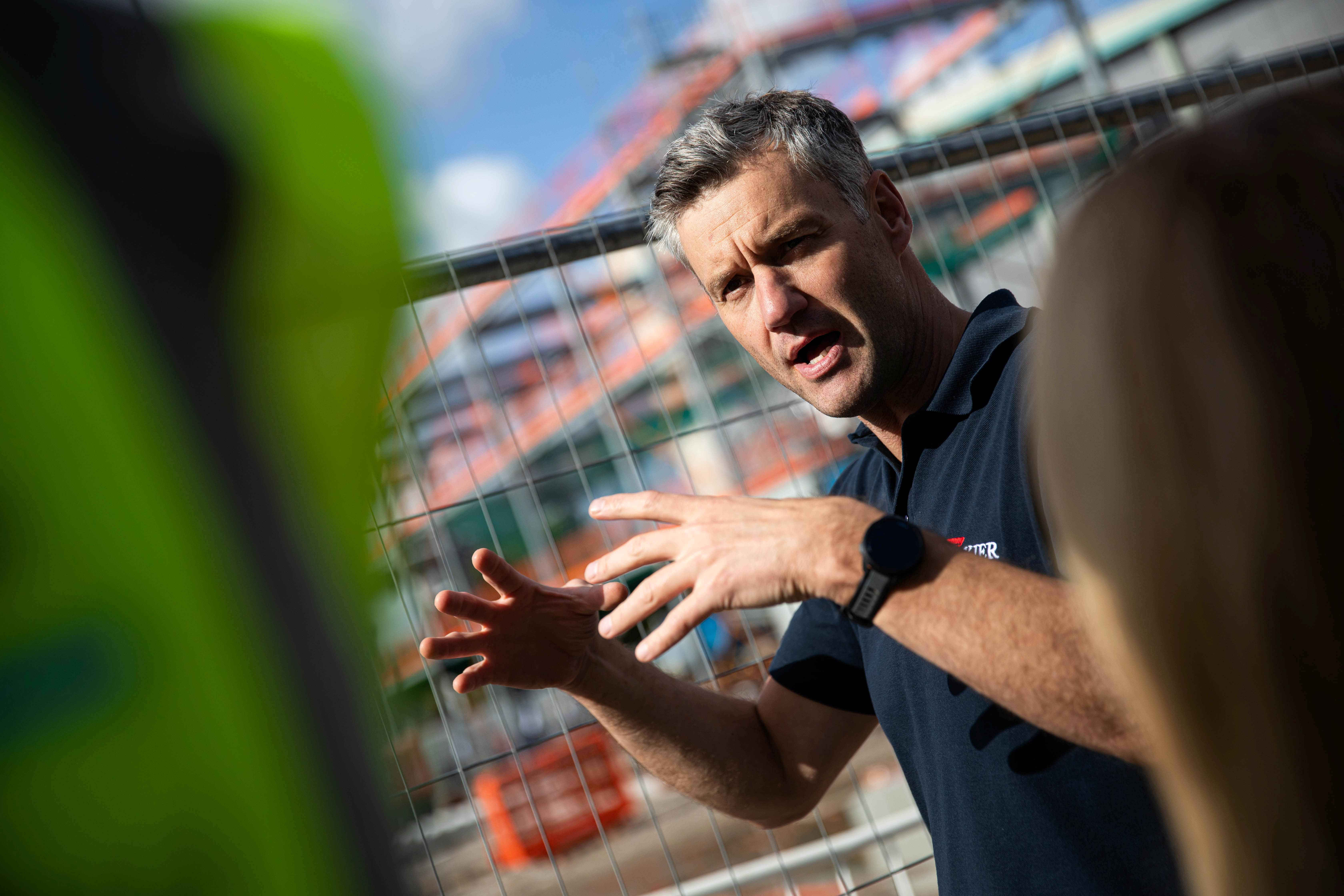 Man talking to group of students at building site 
