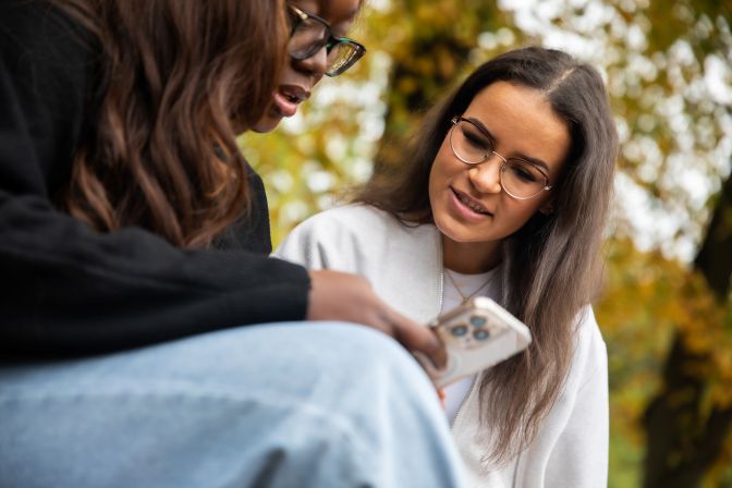 Two student content creators looking at a phone