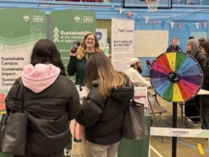 People standing at a Sustainability Team stall at a fair.