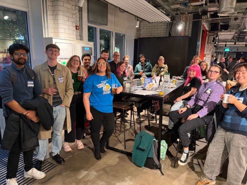 A group of people holding drinks and smiling in the Old Fire Station.