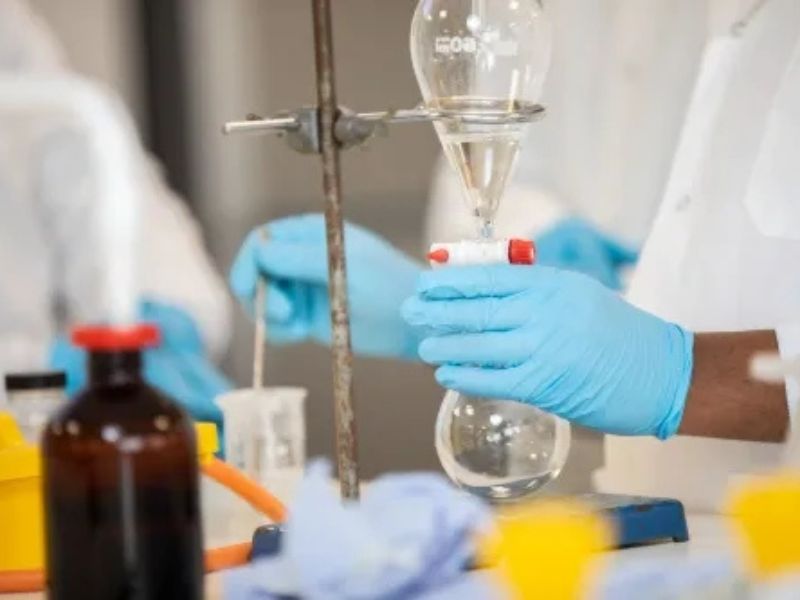 Technician holding a conical flask in the lab with gloved hands