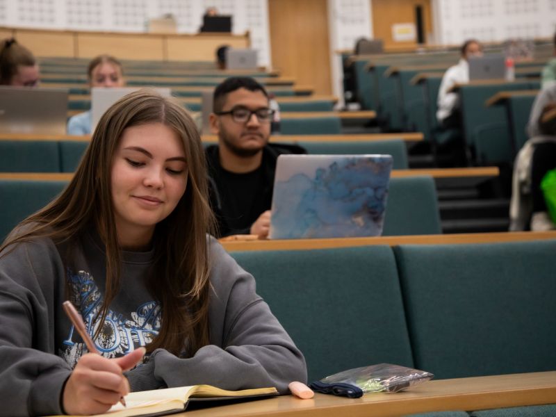 Students studying with laptops and notepads during a lecture