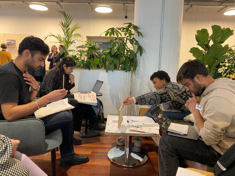 Four students sat around a table working on laptops on a group project.