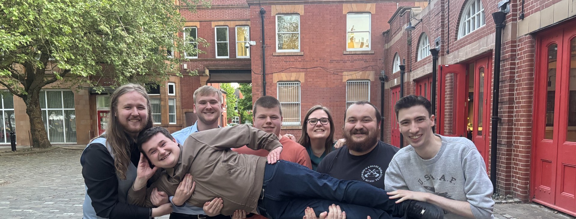 Group of people standing outside of red-brick building 