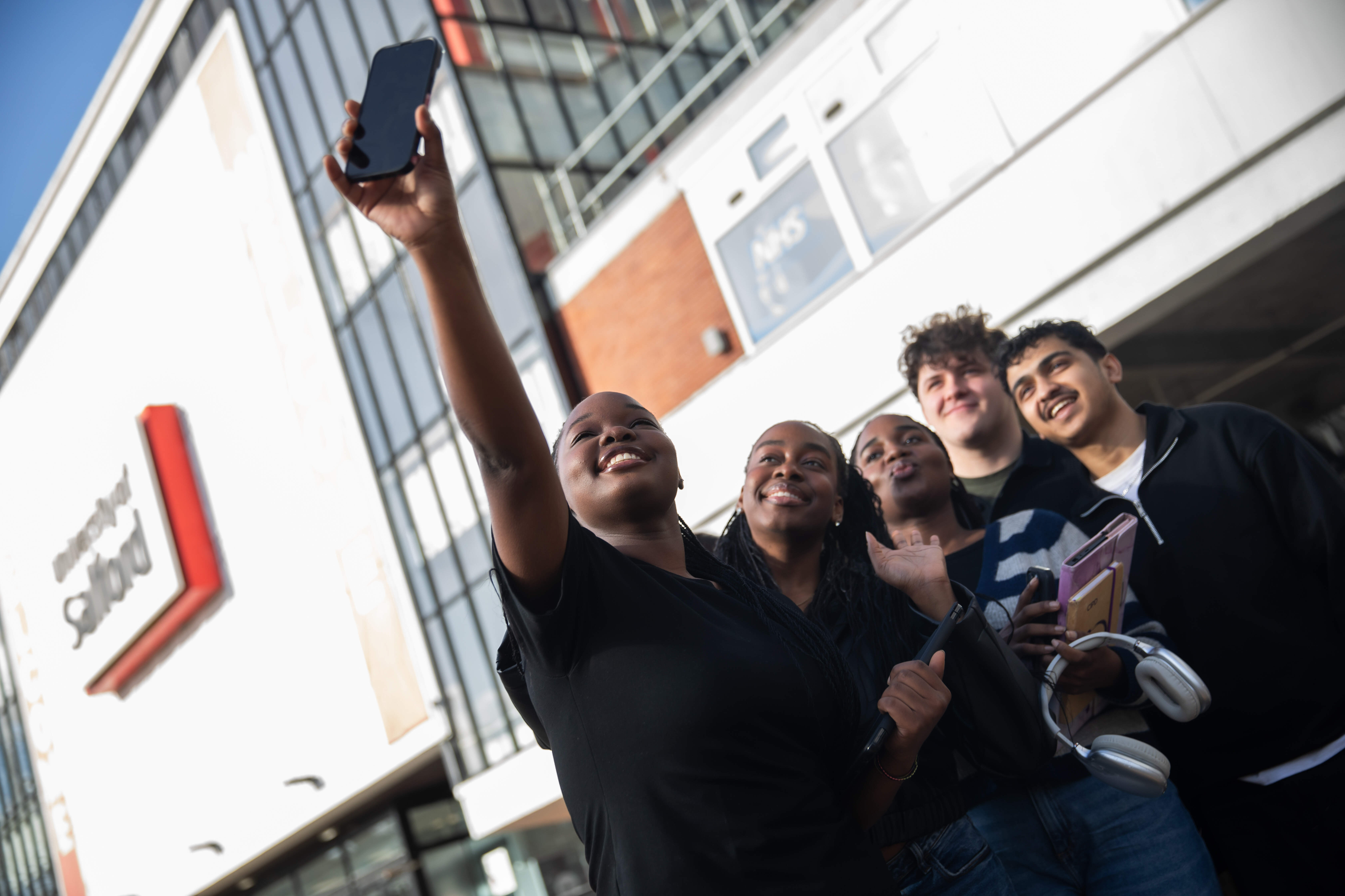 Five students stood outside Maxwell Buiding taking a selfie 