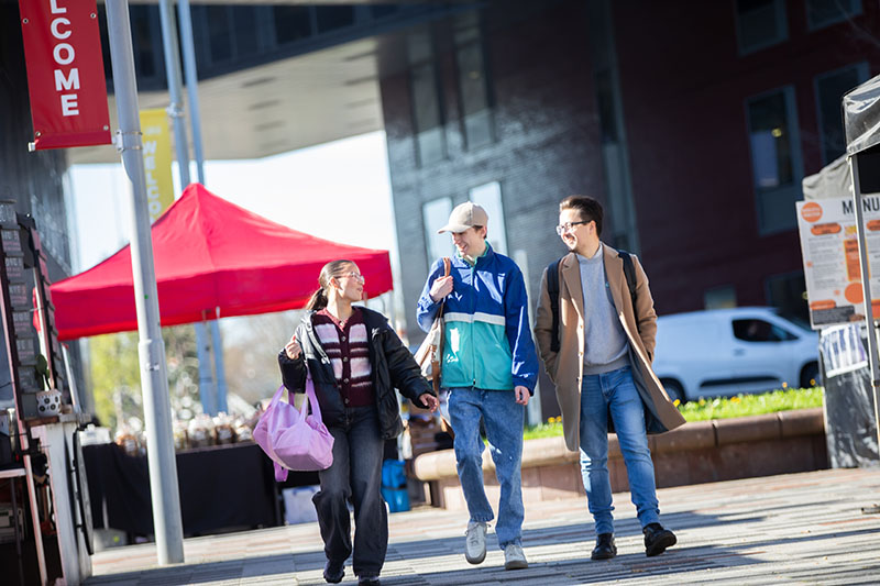 Three students walking through Chapman Square