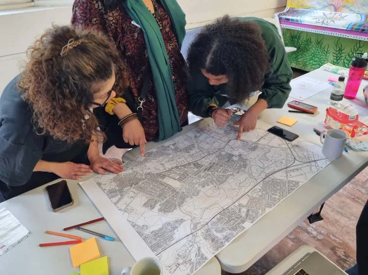 three women leaning over a table looking at a map