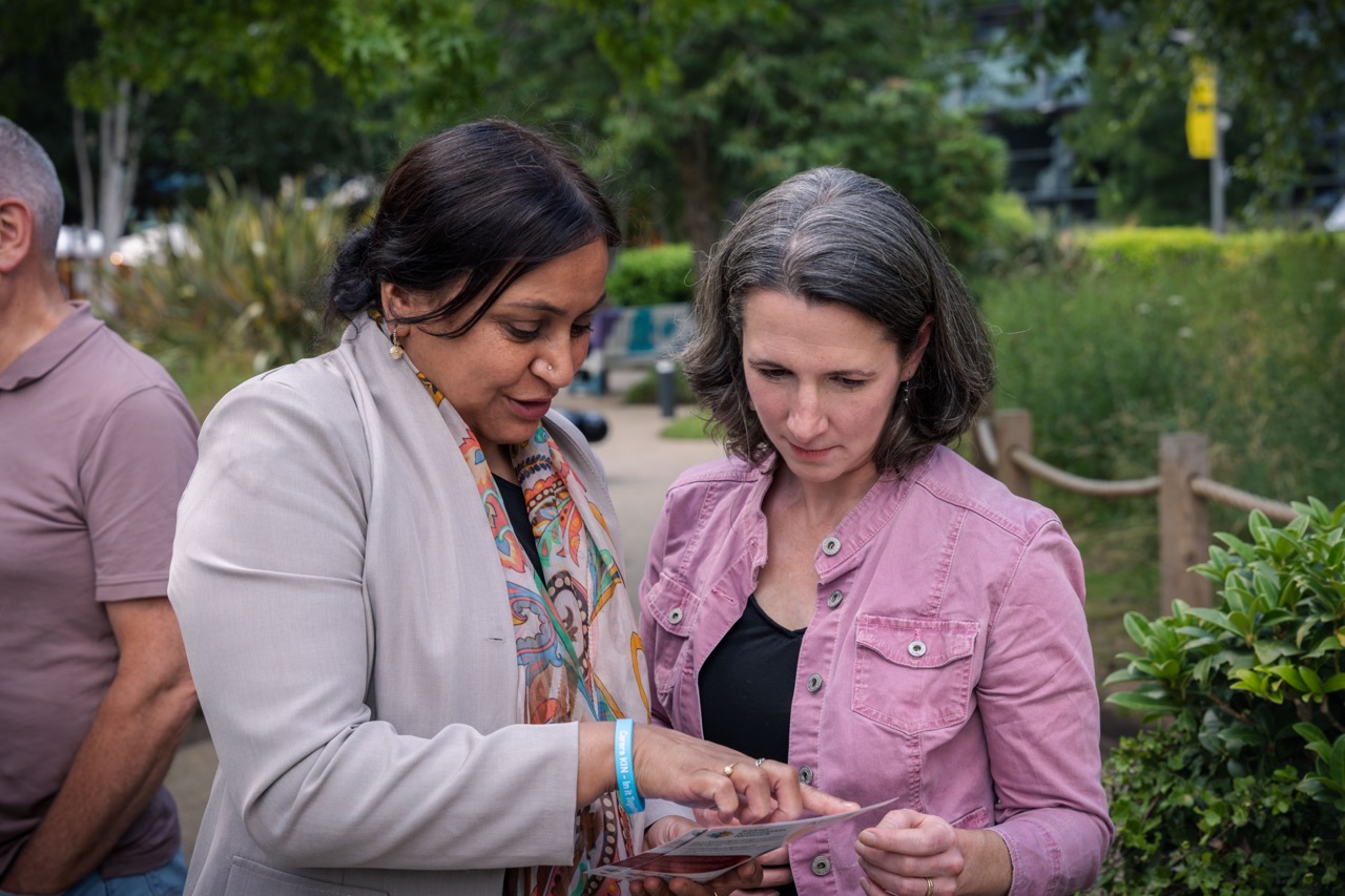 This image shows two individuals observing something closely while outdoors in a garden setting