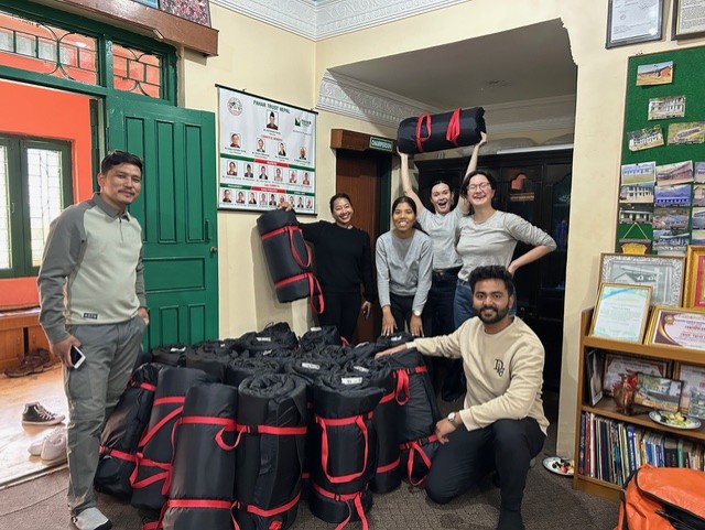 A group of people smiling around a big pile of mats.