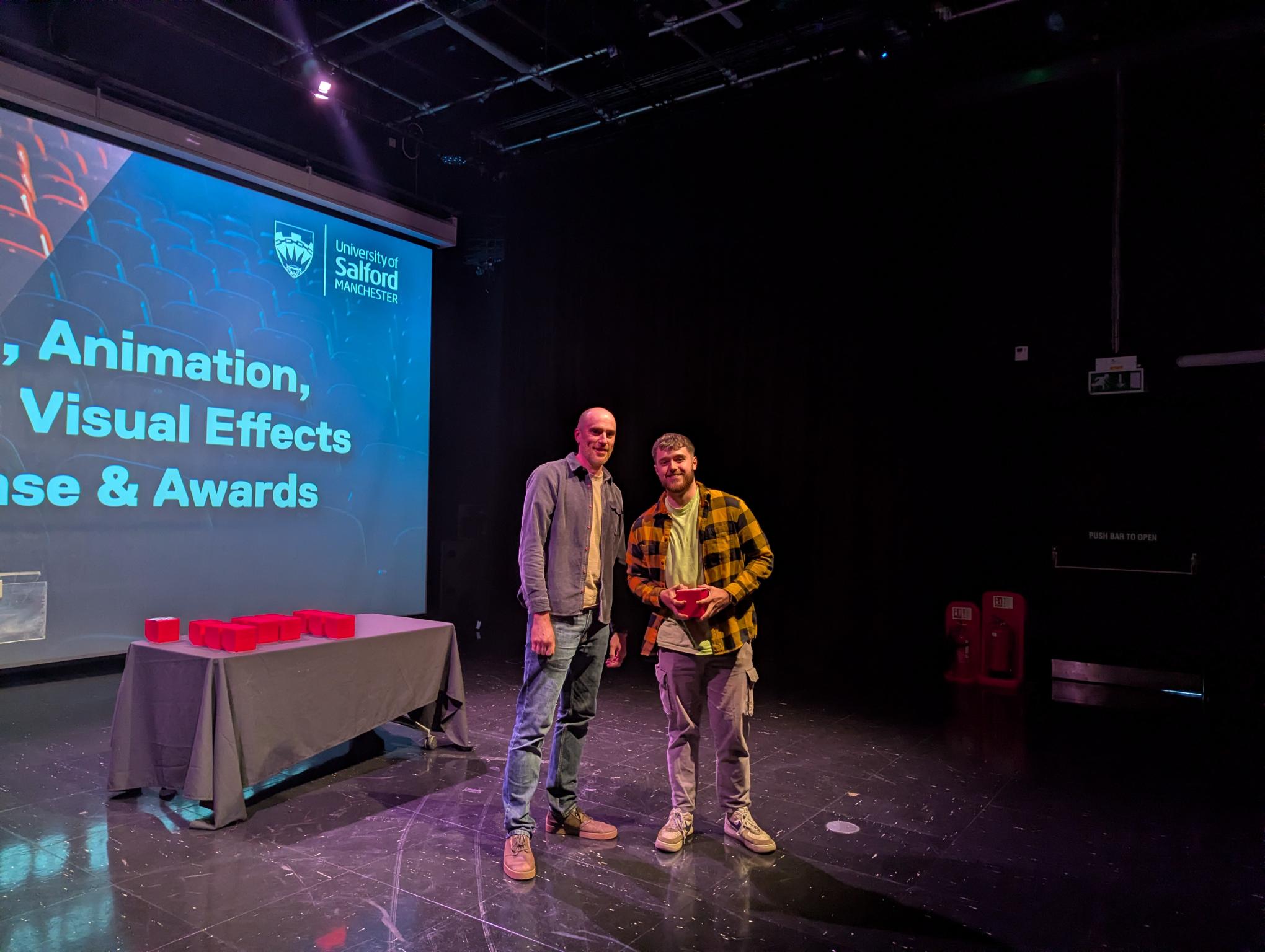 Student accepting their award on stage with their tutor