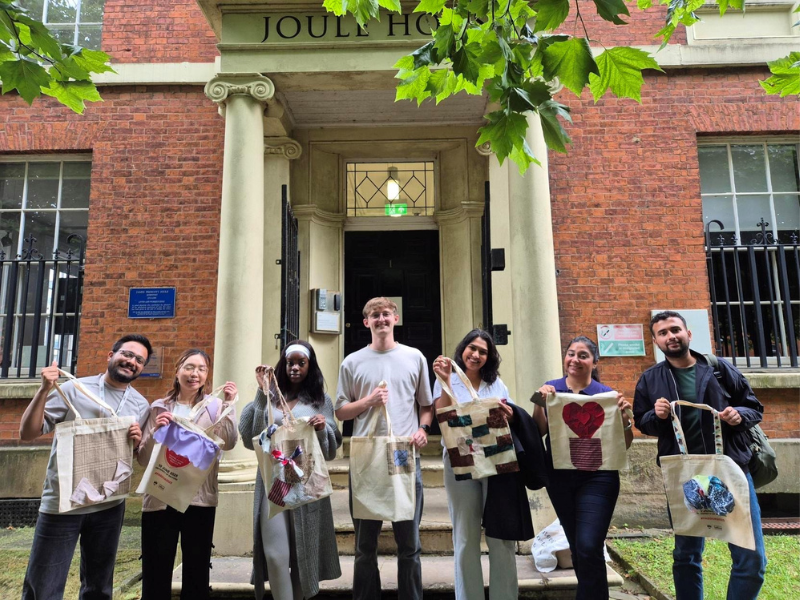A group of University of Salford students holding their custom DIY tote bags outside Joule House