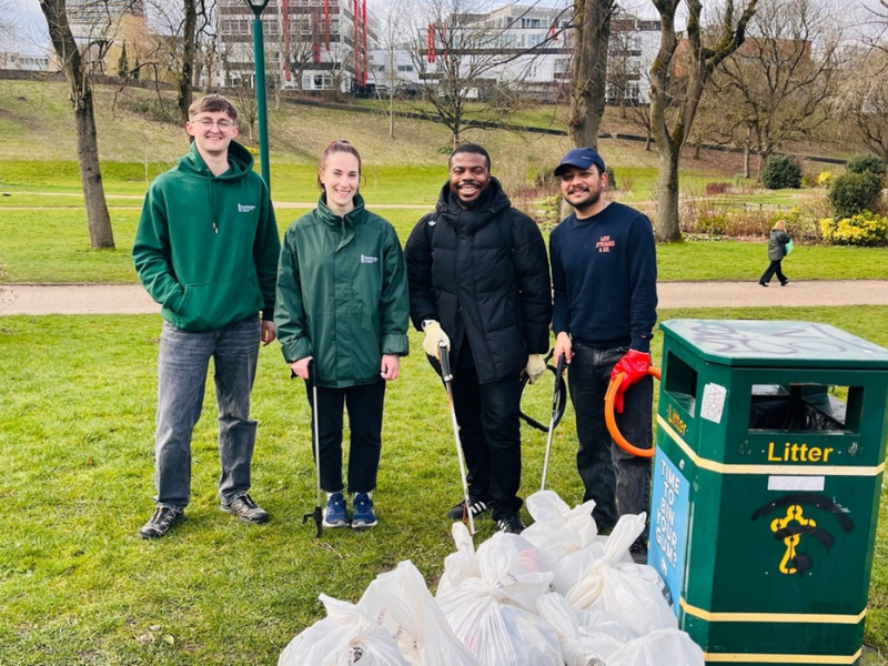 Four volunteers participating in a community litter pick at Peel Park, part of the University of Salford Campus