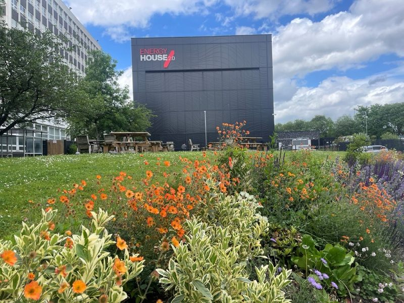 Flowers and grass area in front of the Energy House 2.0 research facility at the University of Salford