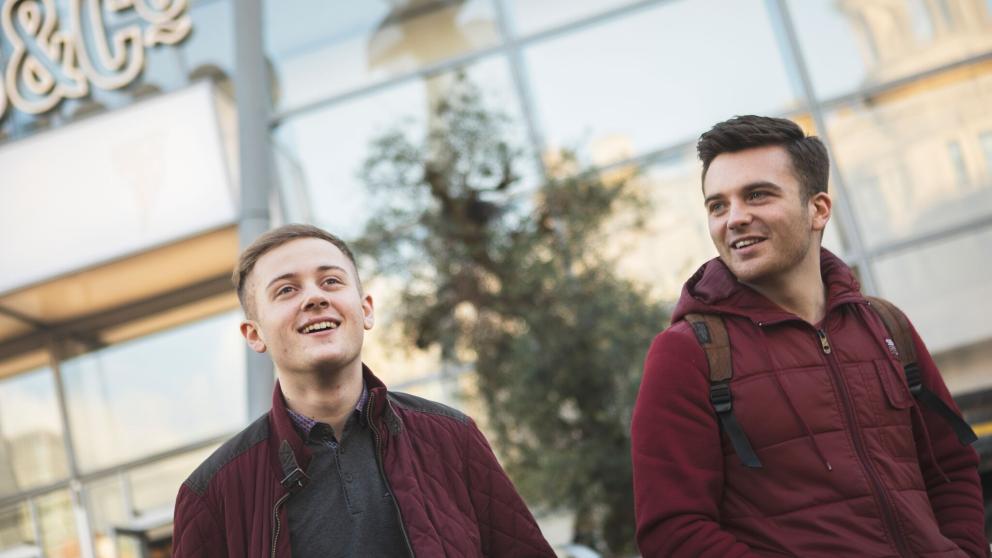 Two students shopping in Manchester city centre standing outside of Selfridges