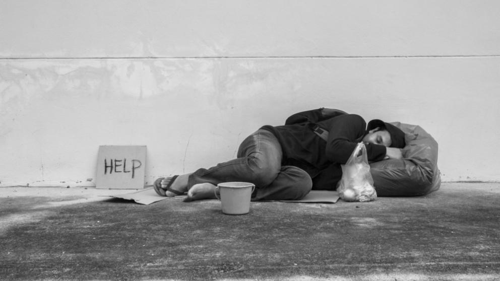 A person experiencing homelessness sleeping on a sidewalk