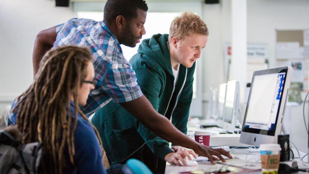 Three students looking at a computer screen