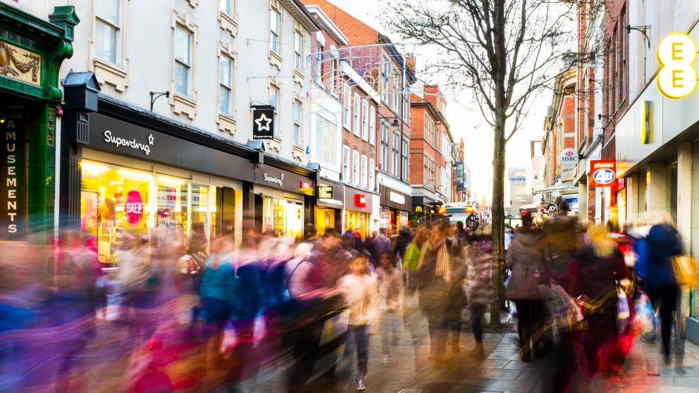 Pedestrianised high street filled with a motion-blurred crowd of shoppers