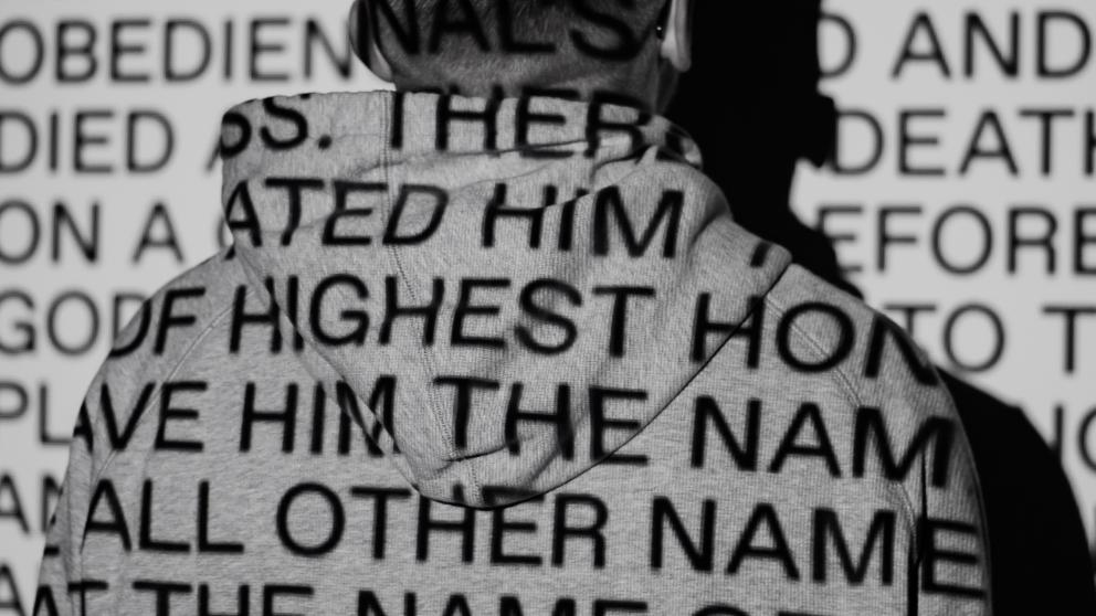 Projected words on the back of a man wearing a hoodie