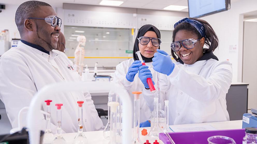 Three students in a practical session in the Bodmer Labs, University of Salford