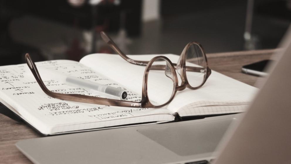 Reading glasses rest on a notebook