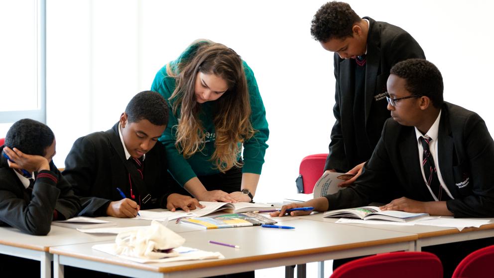 Children and staff member collaborating around a table in a school setting