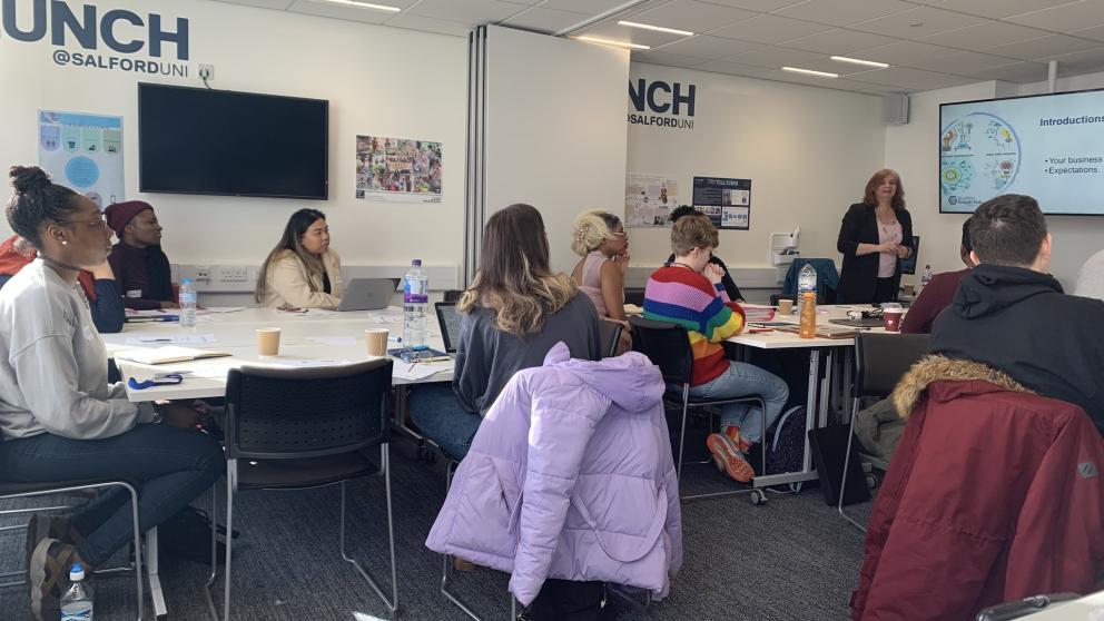 An image showing Launch users sat at desks in a classroom, paying attention to a speaker in front of a Smart board.